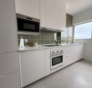 a kitchen with white cabinets and a stove top oven at A Nossa Casa da Costa in Costa da Caparica