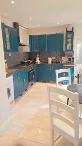 a kitchen with blue cabinets and a table and a chair at Glory room ensuite in Slough