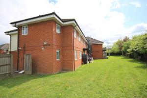 a red brick building with a grass yard at Bath Road Place in Harmondsworth