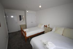 a bedroom with two beds with white sheets and a tv at Bath Road Place in Harmondsworth
