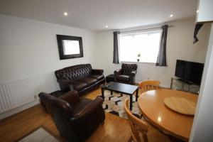 a living room with leather furniture and a table at Bath Road Place in Harmondsworth