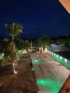 a beach at night with palm trees and green lights at Casa Ilhéus Pousada in Ilhéus