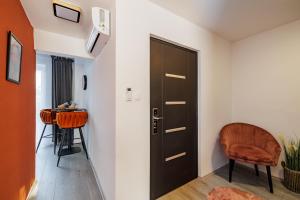 a hallway with a door and a chair and a table at Deluxe Design Apartman in Debrecen