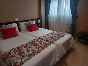 a bedroom with two beds with red pillows at Hotel Restaurante Oviedo in Luarca