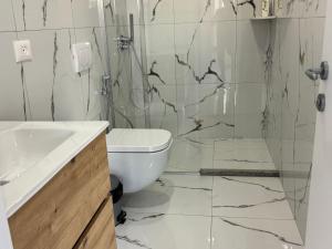 a white bathroom with a toilet and a shower at Restorant Hotel Niku in Draç