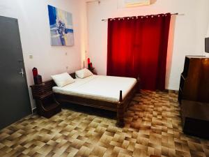 a bedroom with a bed with a red curtain at Hotel Chez Fanny in Palimé