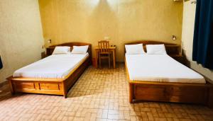 two twin beds in a room with a table at Hotel Chez Fanny in Palimé +3 photos