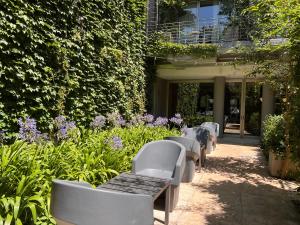a row of benches in front of a building with flowers at Palo Santo Hotel in Buenos Aires