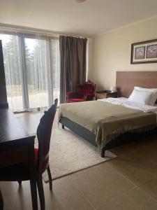 a bedroom with a bed and a chair and a window at Vitál Guesthouse in Almamellék