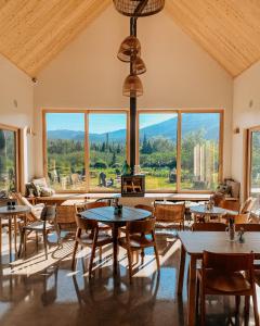 a dining room with tables and chairs and large windows at Farouche Tremblant Cabines nature avec bain nordique in Lac-Superieur