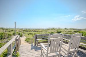 two chairs and a bench on a wooden walkway to the beach at Linger Longer in Caswell Beach