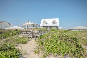 a house on top of a beach with a wooden walkway at Linger Longer in Caswell Beach