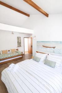 a white bedroom with a large bed and a couch at Morada dos Ventos Búzios in Búzios