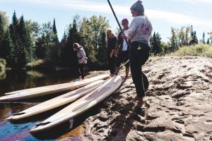 a group of people standing on a beach with surfboards at Farouche Tremblant Cabines nature avec bain nordique in Lac-Superieur +22 photos