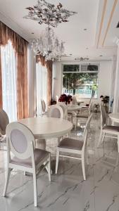 a dining room with white tables and chairs and a chandelier at Villa Kliven in Durrës