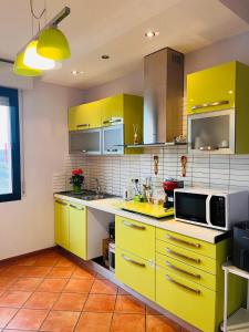 a kitchen with yellow cabinets and a microwave at Affittacamere Cà Bianca in Casa Rossa