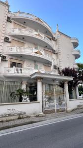 a large white building with balconies on a street at Villa Kliven in Durrës +20 photos