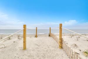 a sandy beach with a fence and the ocean at Lisa Lu in Oak Island