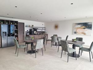 a dining room with tables and chairs and a kitchen at Residence Gloria Dei in Schenna