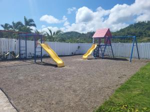 a playground with two swings and a slide at Beit Elohim in Lucea