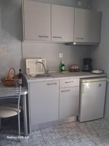 a kitchen with white cabinets and a sink at Irina's Stoudio 7 in Psakoudia