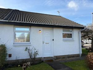 a white house with a white door and windows at Stillrovin Cottage in Stirling