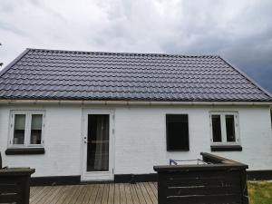 a white house with a black roof on a wooden deck at Small House ærø in Marstal