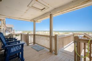 a porch with a blue chair and a view of the ocean at Lowe Tide in Oak Island