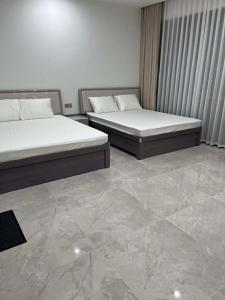 two beds in a room with a marble floor at Villa Ban Mai in Tài Xá