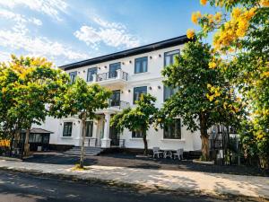 a white building with trees in front of it at Hotel Gia Hưng in Bảo Lộc