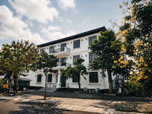 a white building with trees in front of it at Hotel Gia Hưng in Bảo Lộc