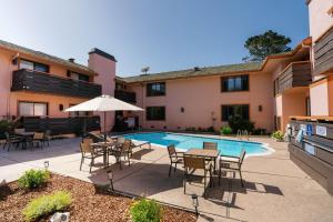 a patio with tables and chairs next to a pool at The Monarch Resort in Pacific Grove