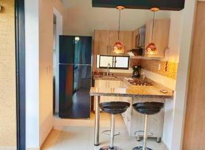 a kitchen with a counter with two stools and a sink at Descanso y confort in La Tebaida