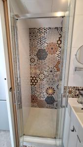 a shower with a glass door next to a sink at Petite Maison indépendante. in Béziers