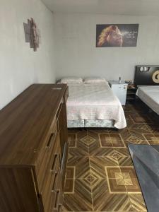 a bedroom with a bed and a wooden dresser at Pousada Jangarelli in Guaíra