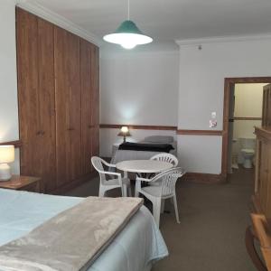 a hotel room with a bed and a table and chairs at Lekkerrus guesthouse in Krugersdorp