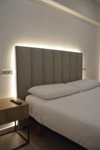 a bed with a large headboard next to a table at Hotel Marín in Marín
