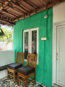 two chairs sitting on the porch of a green house at Search hurt stays in Kuilapayam