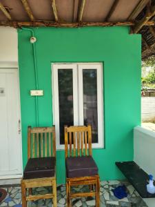 two chairs in a room with a green wall at Search hurt stays in Kuilapayam