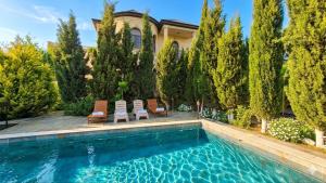 a swimming pool with two chairs and a house at Green Garden Shuvelan in Baku