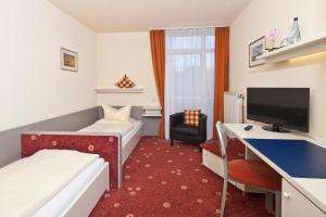 a hotel room with two beds and a desk at Akzent Hotel Höhenblick in Mühlhausen im Täle