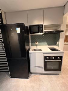 a kitchen with a black refrigerator and a sink at Apartamento Studio in Arujá