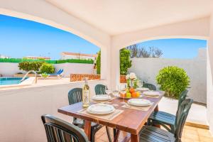 a dining table and chairs on a patio with a pool at Villa San Jose by Villa Plus in Cala en Porter