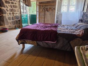 a bed in a room with a wooden floor at la maisonnette in Fontanges