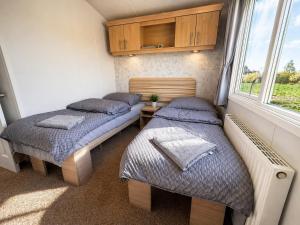 two beds in a small room with a window at FarmaKolonia2 in Zabiele
