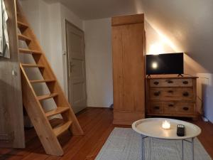 a living room with a staircase and a tv and a table at Freilandhof in Ötisheim