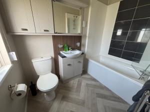 a bathroom with a toilet and a sink and a bath tub at Hardys Caravan Park in Ingoldmells