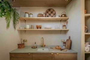 a kitchen with a sink and shelves with ceramics at The Nook Guest House in Letchworth +9 photos