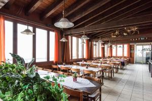 un restaurante con mesas de madera, sillas y plantas en Berghotel Bonistock en Frutt