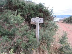 a sign on the side of a dirt road at Kestrel, Longhouse Cottages in Rosemarkie